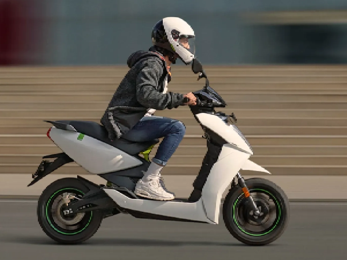 Rider on white Ather 450 electric scooter side riding shot