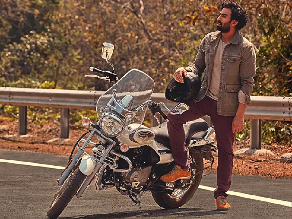 Rider standing beside Bajaj Avenger Cruise 220 on highway