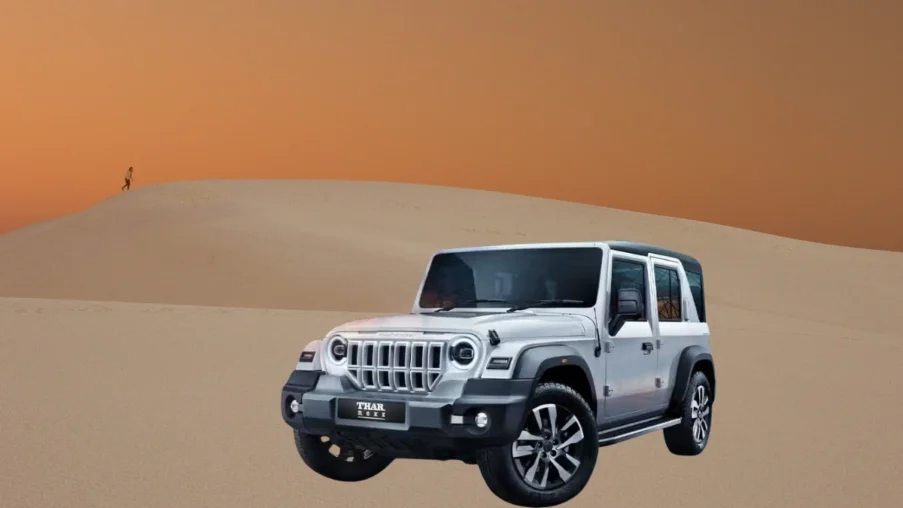 Mahindra Thar Roxx SUV in white parked on desert dunes, highlighting its rugged off-road design, boxy stance, and alloy wheels.